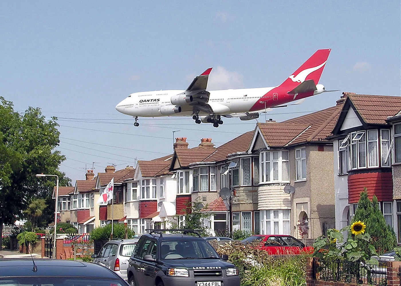 A Qantas Boeing 747-400 approaching runway 27L at London Heathrow Airport, England. The houses are in Myrtle Avenue, at the south east corner of the airport.